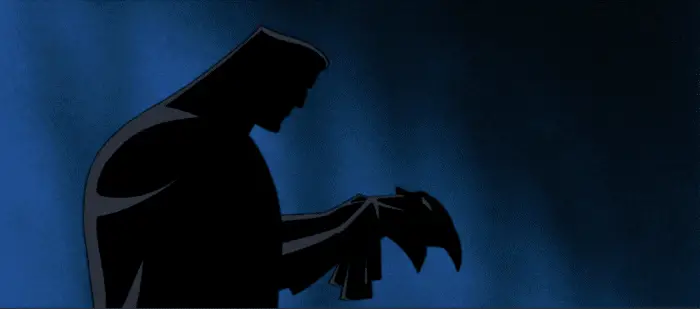 A silhouette of Bruce Wayne holding the Batman mask