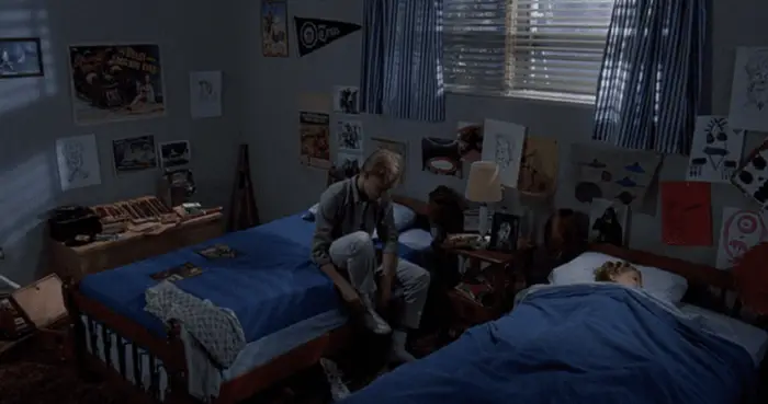 Two boys go to sleep in their bedroom decorated with monster-movie drawings and collectibles