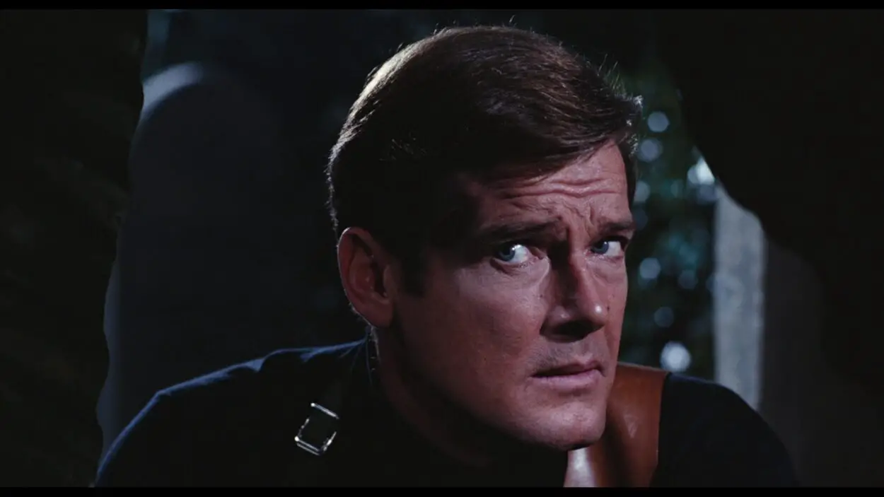 Roger Moore plays James Bond, looking over his shoulder.
