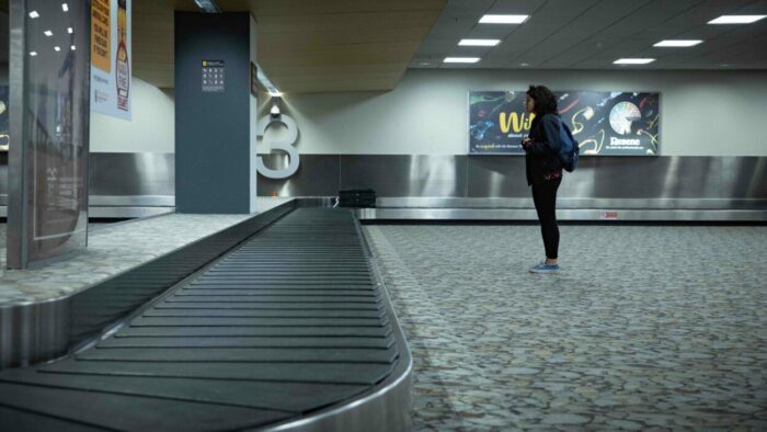 A woman waits for bags to arrive at baggage claim.