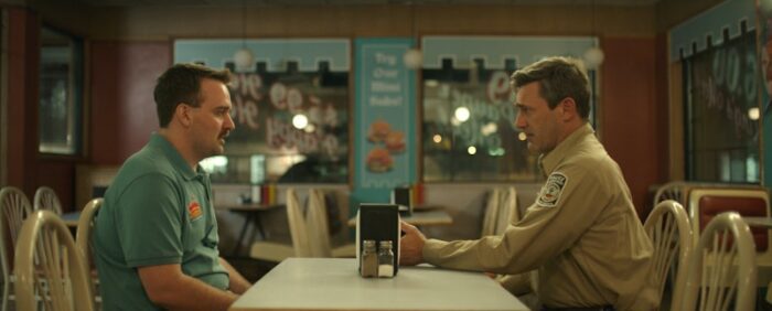 Micah Stock and Jon Hamm as Jay Moore and Sherif Sanders in Maggie Moore(s) (2023). From Screen Media Films.