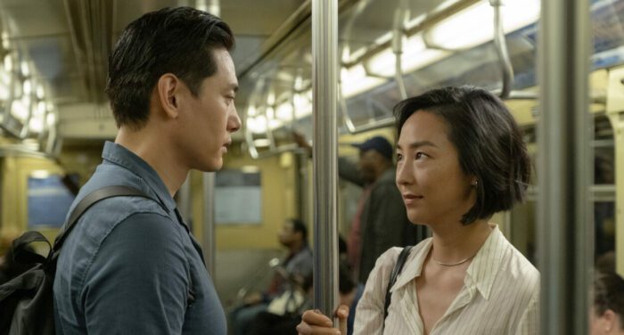 A man and a woman face each other on a subway.