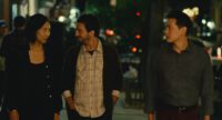 Nora (Celine Song), Arthur (John Magaro), and Hae Sung (Teo Yoo) walk on a New York City sidewalk at night with lights in the background.