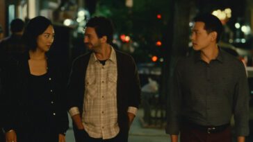 Nora (Celine Song), Arthur (John Magaro), and Hae Sung (Teo Yoo) walk on a New York City sidewalk at night with lights in the background.