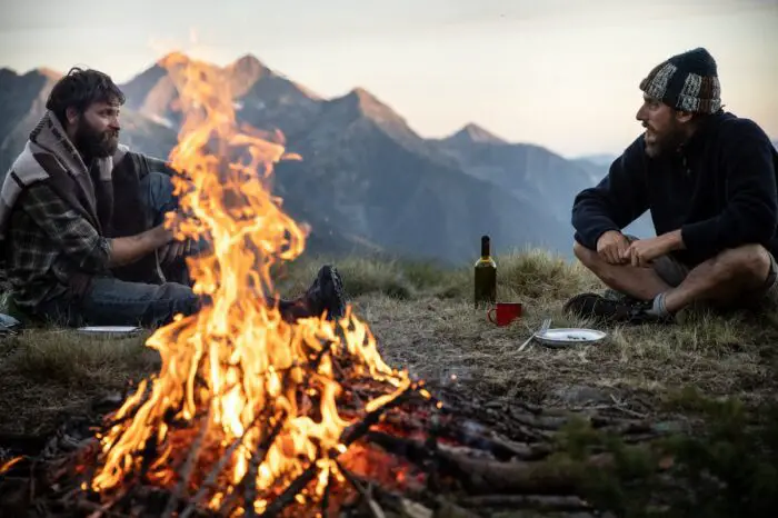 Two men enjoy a campfire in the mountains.