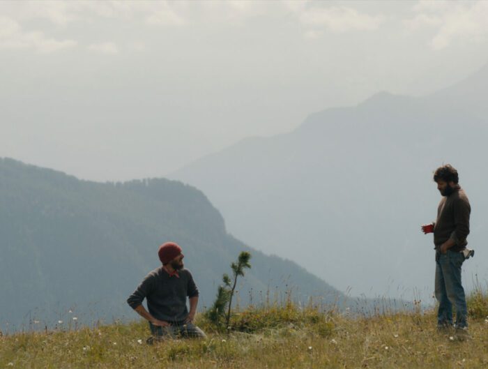 Two men in a field in front of distant mountains.