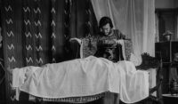 A magician levitates a woman in a bed.