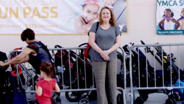 Director Therese Shecter stands in front of a rack of baby carriages.