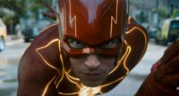 The Flash (Ezra Miller) gets into his running stance while wearing his red costume with yellow lightning streaks.