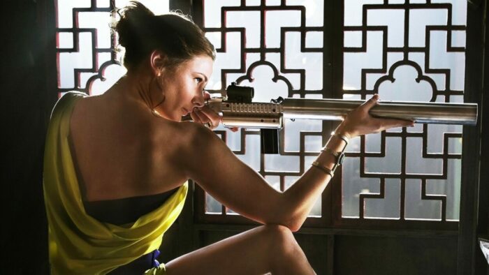 Image from MISSION: IMPOSSIBLE ROGUE NATION showing Rebecca Ferguson as Ilsa Faust aiming a gun disguised to look like a musical instrument. 