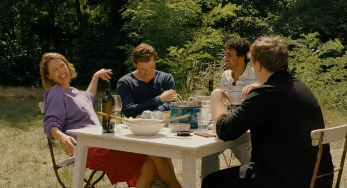 A woman and three young men enjoy an outdoor meal.