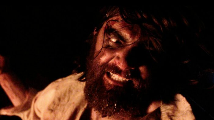A bloodied man grimaces in rage in Belle