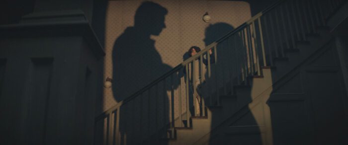 Image from COBWEB. Shows a boy standing on a staircase surrounded by shadows of his parents.