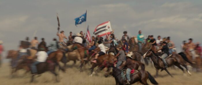 Lakota people on horses with flags.