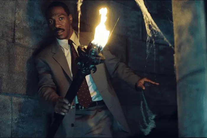 The Haunted Mansion: Jim Evers (Eddie Murphy) with a torch in a stone hall.