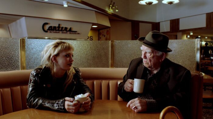 A young woman and an old man share conversation in a diner.