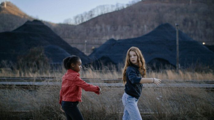 Gabrielle Wilson and Lanie Marsh dance by piles of coal