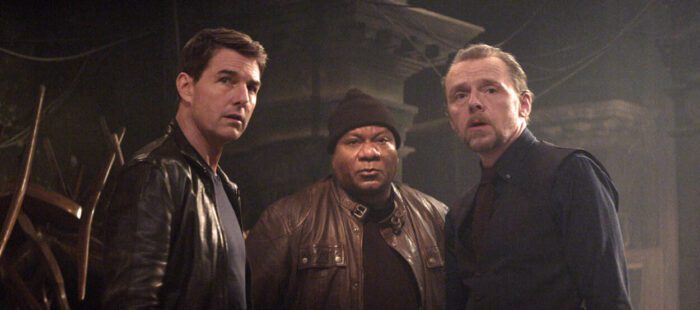 Three men look towards a new ally in an underground room.