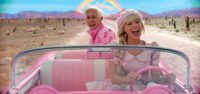 Two people ride in a pink convertible and sing together in Barbie.