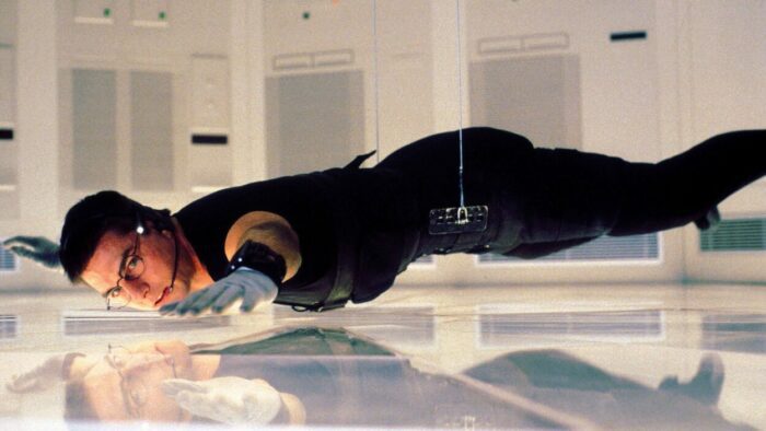 Image from MISSION: IMPOSSIBLE showing Ethan Hunt hanging by two thin strings just centimeters above the floor of a top secret CIA vault. 