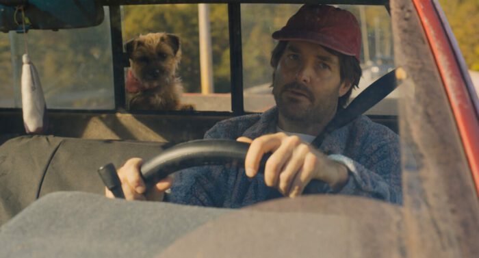 Doug (Will Forte), wearing a red trucker hat, drives his pick-up truck with Reggie loose in the open trunk as they play "fetch and f—k."