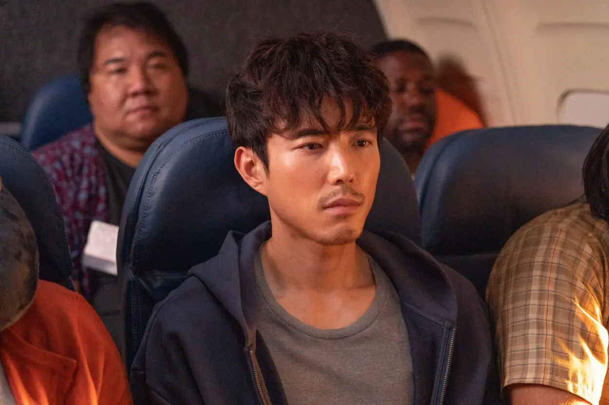 A perturbed man sits in a middle seat on an airplane in Shortcomings