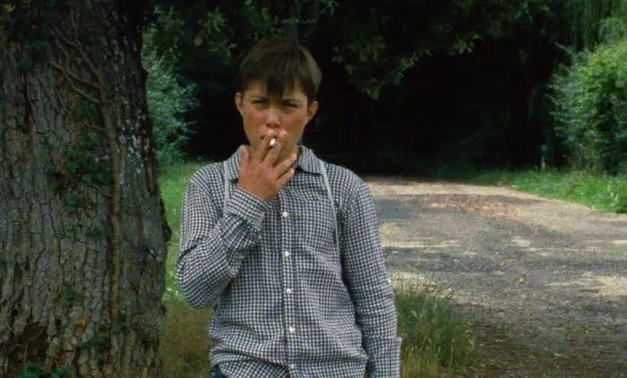 A boy smokes a cigarette.