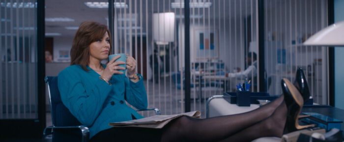 Robbie (Elizabeth Banks) sits in her office, feet propped up on the desk, with a cup of coffee. She stares off into space as if planning her next business venture.