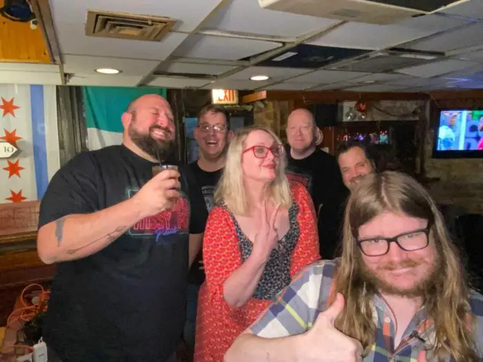 Six film critics pose for a picture in a bar before a Cinephile Hissy Fit podcast.