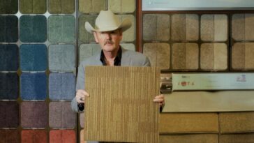 A middle-aged man in a cowboy hat models carpet samples.