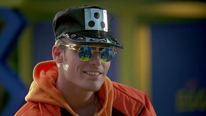 Close-up of Johnny wearing a jacket with sunglasses and a black ball cap with a metal bill.