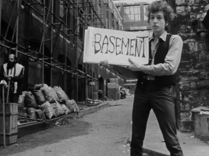 Bob Dylan holds up a placard reading "BASEMENT" in Dont Look Back.