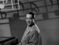 Duke Ellington sits at the piano on a Soundies set for "Hot Chocolate."