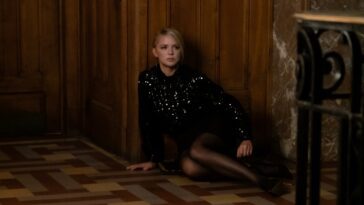 Judith, wearing a sequined black dress, sitting on the floor.