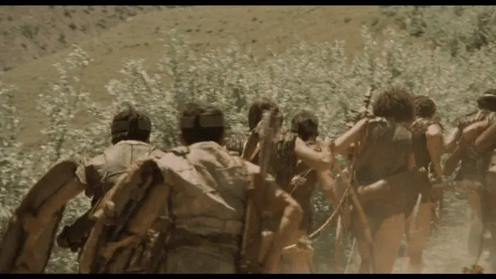 A troop of soldiers tramples across the bush.
