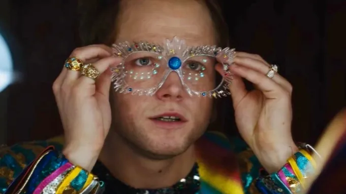 Taron Edgerton adjusts his glasses as Elton John in Rocketman.