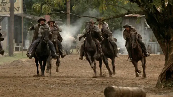 The Long Riders ride through town on horseback firing guns.