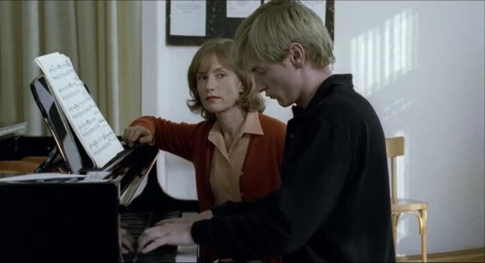A young man playing piano and a woman sitting next to him and looking at him
