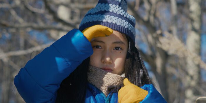 A young girl looks directly at the camera in Evil Does Not Exist playing at TIFF