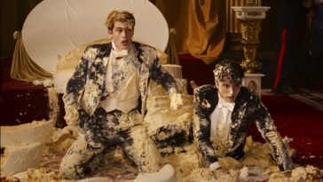 Nicholas Galitzine as Prince Henry and Taylor Zakhar Perez as Alex Claremont-Diaz shocked crouched on the floor covered in cake