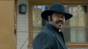 A man in a priest's outfit looks to his right in Outlaw Johnny Black