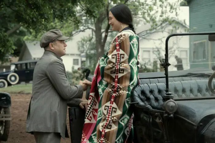 Mollie exits her car as Ernest offers his hand to help her get out of the 1920s car.