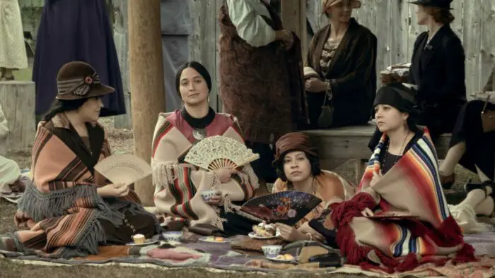 Mollie sits her sisters as they all wear ornate shawls and cool themselves with handheld fans.