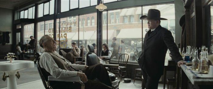 William Hale sits on a barber chair while Tom White (Jesse Plemons) of the Bureau of Investigation questions him about the murders in Osage Nation.