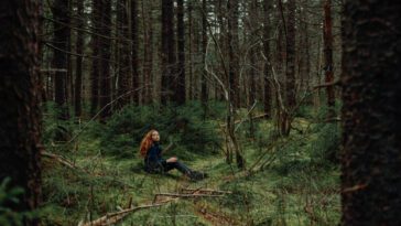 A young girl sits in a forest.