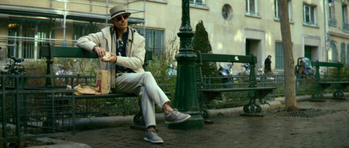 A man sits on a park bench with his leg up.