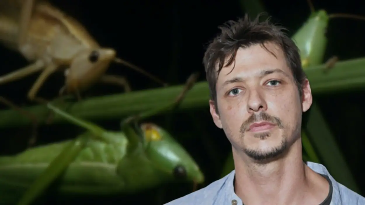 Daniel McCabe in front of an image of grasshoppers from his film Grasshopper Nation.