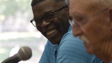 Jimmie and De share a laugh at a microphone in a still from A Binding Truth.