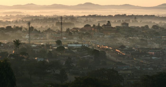 A long shot of the Ugandan countryside overlooking a village at daybreak.
