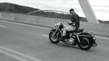 Austin Butler as live wire motorcyclist Benny riding down a highway